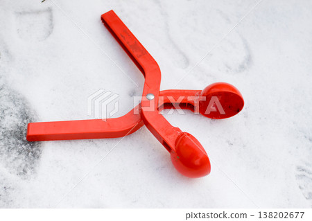 Bright red plastic device, toy clip for making snowballs on white snow background. Happy childhood and winter fun game concept. 138202677