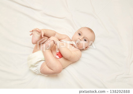 Caucasian Baby In Diaper With Pacifier On White Sheets Showing Joy And Playfulness 138202888