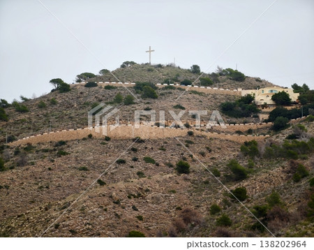 Hilltop hike journey, Tranquil journey up uneven terrain to spiritual landmark under subdued sky 138202964