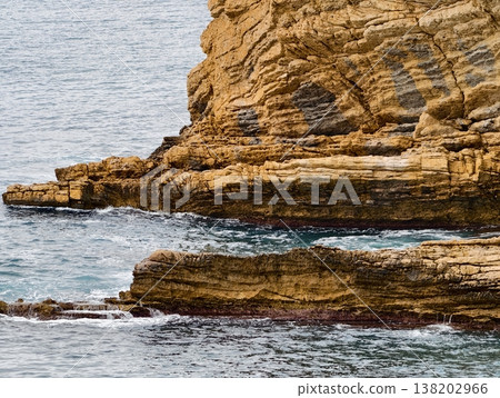 Cliffs meet tranquil ocean background, Vertical stratification of cliffs with serene sea backdrop Cliffs meet tranquil ocean background, Vertical stratification of cliffs with serene sea backdrop 138202966