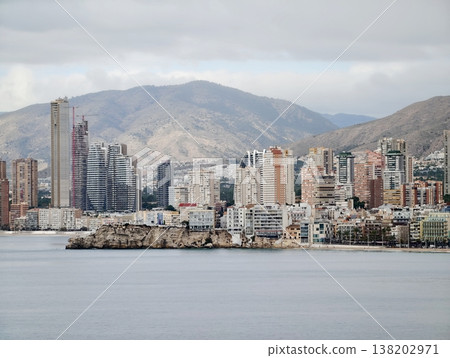 Skyline with mountains, Seaside city skyline featuring tall buildings and cloudy mountain backdrop Skyline with mountains, Seaside city skyline featuring tall buildings and cloudy mountain backdrop 138202971