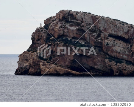 Rough cliffs meet tranquil waters, Jagged cliffs intersect smooth water with visible erosion features 138202980