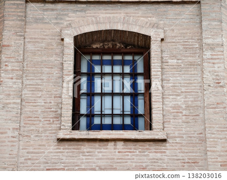 Vintage brick window with iron grille, Aged brick setting with metal grille and textured masonry wall 138203016