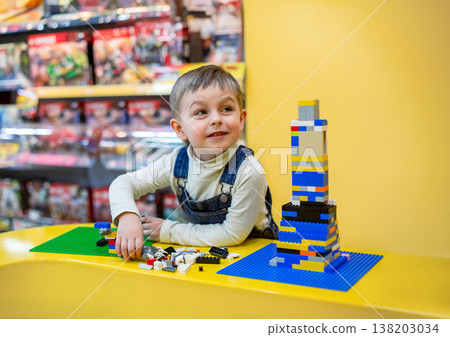 Little boy focused on assembling colorful building bricks bright table inside toy store environment Little boy focused on assembling colorful building bricks bright table inside toy store environment 138203034