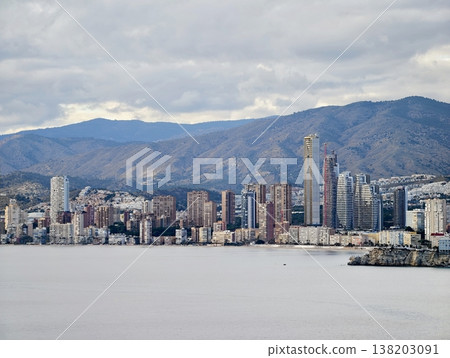 Metropolitan landscape with distant hills, Skyscrapers against mountain backdrop and floating clouds Metropolitan landscape with distant hills, Skyscrapers against mountain backdrop and floating clouds 138203091