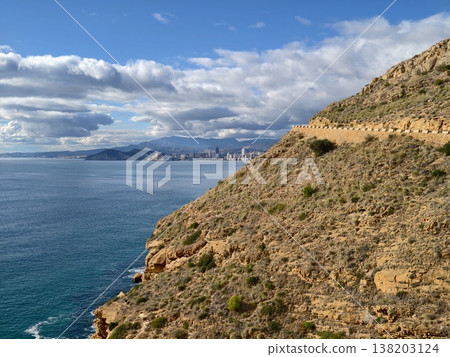 Path overlooking ocean and remote settlement, Scenic hillside walk toward sea with nearby village view 138203124