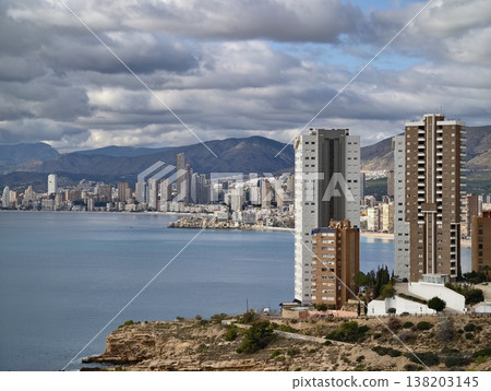 Skyscrapers touch sky, Vertiginous residential blocks slope towards bustling waters beneath stormy clouds 138203145