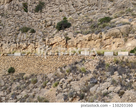 Layered stones with erosion and vegetation, Macro view revealing rugged textured wall with natural erosion Layered stones with erosion and vegetation, Macro view revealing rugged textured wall with natural erosion 138203160