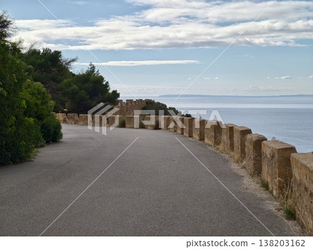 Charming winding street by calm sea offering spectacular sunset scenery for relaxed excursions Charming winding street by calm sea offering spectacular sunset scenery for relaxed excursions 138203162