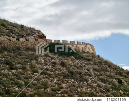 Old fortress on ridge, Ancient stone citadel located on ridge displaying battlements and weathered masonry Old fortress on ridge, Ancient stone citadel located on ridge displaying battlements and weathered masonry 138203169