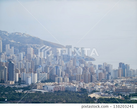 Vertical structures at shoreline merge with misty hills and rocky terrain creating layered scenic composition Vertical structures at shoreline merge with misty hills and rocky terrain creating layered scenic composition 138203241