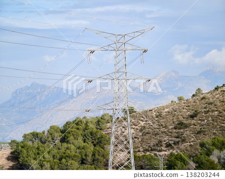 Sunlit pylons amid nature, Infrastructure bridges rural power with scenic mountain environment 138203244