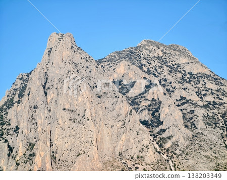 Bright sunlight gracefully highlights rugged limestone mountains and majestic summits ahead 138203349