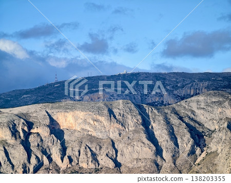 Illuminated cliffside exposing complex stratification and rugged terrain ideal for exploration Illuminated cliffside exposing complex stratification and rugged terrain ideal for exploration 138203355