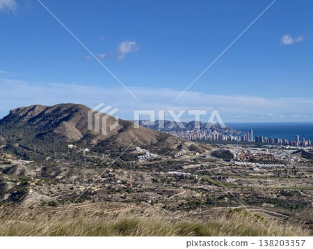 Hiking spot with stunning scenery, Sunlit meadow and winding trail amidst mountain and sea scenery Hiking spot with stunning scenery, Sunlit meadow and winding trail amidst mountain and sea scenery 138203357