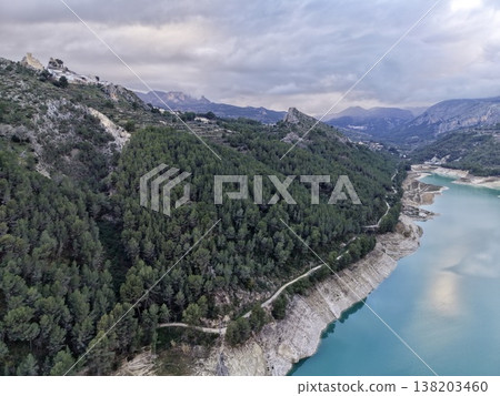 Panoramic aerial image showcasing vivid blue reservoir amid rugged pinecovered slopes and dramatic cliffs Panoramic aerial image showcasing vivid blue reservoir amid rugged pinecovered slopes and dramatic cliffs 138203460