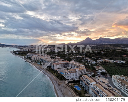 Peaceful evening overlooking beach and distant hills, Calm ocean scene with colorful sky and scenic shoreline Peaceful evening overlooking beach and distant hills, Calm ocean scene with colorful sky and scenic shoreline 138203479