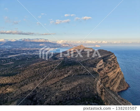 Drone captures sweeping panorama of wild coastal cliffs under radiant sunlight between sky and sea 138203507