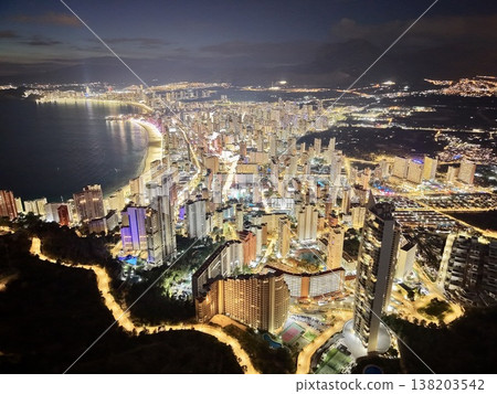 Glowing urban night, Luminous coastal cityscape showcasing vibrant harbor under shimmering night sky 138203542