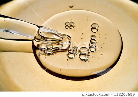 Dropper dispensing golden liquid serum with bubbles 138203699