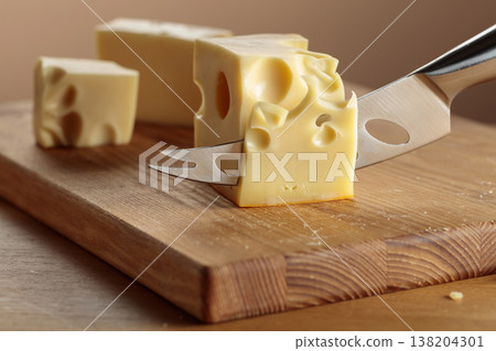 Cheese and knife on a wooden cutting board. Cheese and knife on a wooden cutting board. 138204301