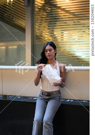 Thai Woman Holding Egg Tart on Hong Kong Street 138204603