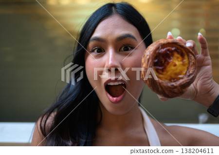 Surprised Young Thai Woman Holding Egg Tart in Hong Kong Surprised Young Thai Woman Holding Egg Tart in Hong Kong 138204611