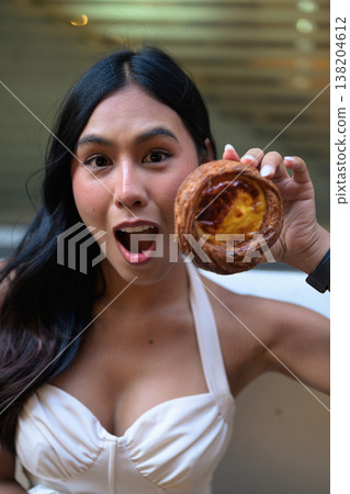Surprised Young Thai Woman Holding Egg Tart in Hong Kong Surprised Young Thai Woman Holding Egg Tart in Hong Kong 138204612
