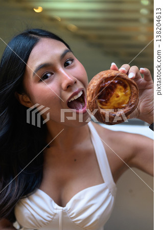 Surprised Young Thai Woman Holding Egg Tart in Hong Kong Surprised Young Thai Woman Holding Egg Tart in Hong Kong 138204613
