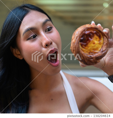 Surprised Young Thai Woman Holding Egg Tart in Hong Kong Surprised Young Thai Woman Holding Egg Tart in Hong Kong 138204614