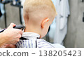 Blond child receiving professional haircut at barbershop 138205423