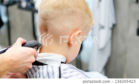 Blond child receiving professional haircut at barbershop Blond child receiving professional haircut at barbershop 138205423