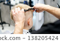 Hairdresser cutting blond child's hair at barbershop 138205424