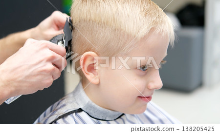Child receiving a haircut from a hairdresser in barbershop Child receiving a haircut from a hairdresser in barbershop 138205425