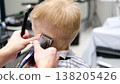 Child getting a haircut with clippers in a barbershop 138205426