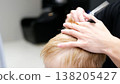 Hairdresser cutting boy's blond hair in barbershop 138205427