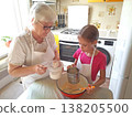 A grandmother and her granddaughter are making pancakes in the kitchen. 138205500