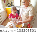 A grandmother and her granddaughter are making pancakes in the kitchen. 138205501