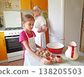 A grandmother and her granddaughter set out the necessary ingredients for cooking on the table. 138205503