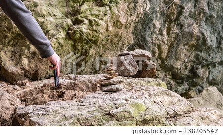 Hand Placing Smartphone Near Stone Cairn on Rocky Ground Hand Placing Smartphone Near Stone Cairn on Rocky Ground 138205547