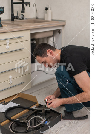 A plumber is replacing a faucet in the kitchen. A plumber is replacing a faucet in the kitchen. 138205828