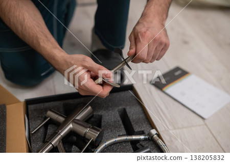 A plumber is replacing a faucet in the kitchen. A plumber is replacing a faucet in the kitchen. 138205832