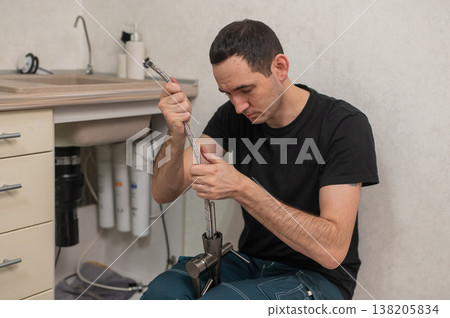 A plumber is replacing a faucet in the kitchen. A plumber is replacing a faucet in the kitchen. 138205834