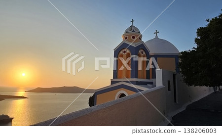 Scenic sunset view of a white and blue domed church overlooking the sea. Scenic sunset view of a white and blue domed church overlooking the sea. 138206003