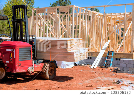 Forklift carries wooden beams at construction site where house is being built. 138206183