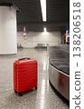 Red suitcase standing on airport baggage claim area near carousel  138206518