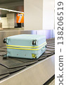 Damaged hard shell suitcase with hole and visible interior on baggage conveyor belt airport close up view. 138206519