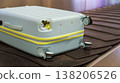 Damaged hard shell suitcase with hole and visible interior on baggage conveyor belt airport close up view. 138206526
