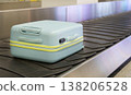 Light blue suitcase moving on airport baggage carousel with metal conveyor system terminal interior. 138206528