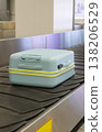 Light blue suitcase moving on airport baggage carousel with metal conveyor system terminal interior. 138206529